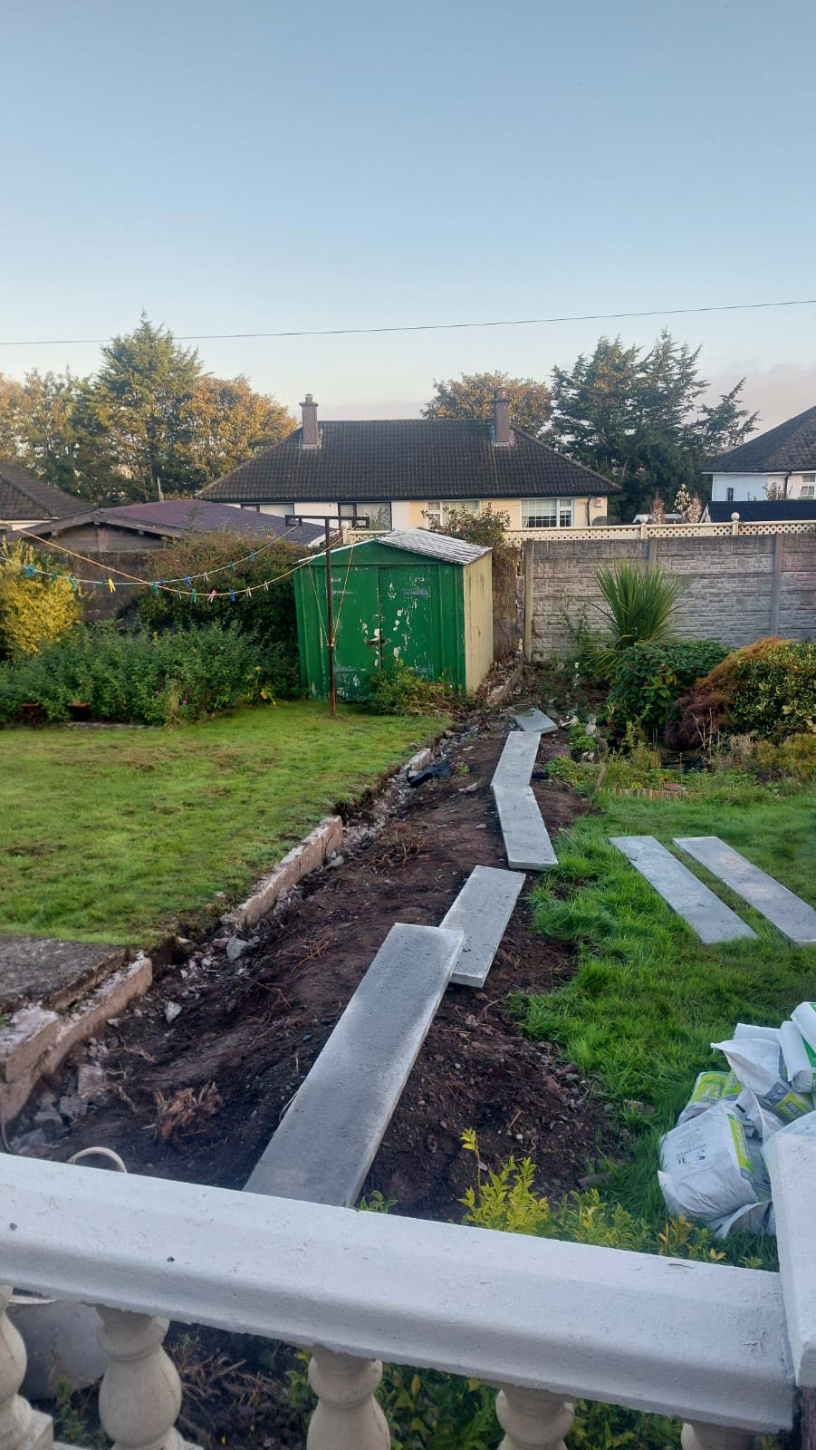Before: Old fence line removed, with the ground dug out and concrete gravel boards laid along the boundary